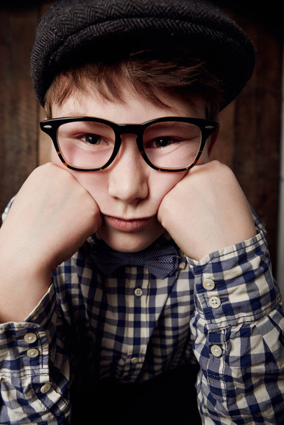 Portrait, glasses and bored kid, sad expression and thinking of depression. Tired face, nerd and young boy child in hat, geek in eyewear or exhausted with learning, serious or stress in New Zealand. - Photo, Image