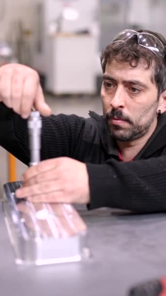 Vidéo d'un travailleur vérifiant la taille des trous sur une pièce métallique dans une usine moderne cnc - Séquence, vidéo
