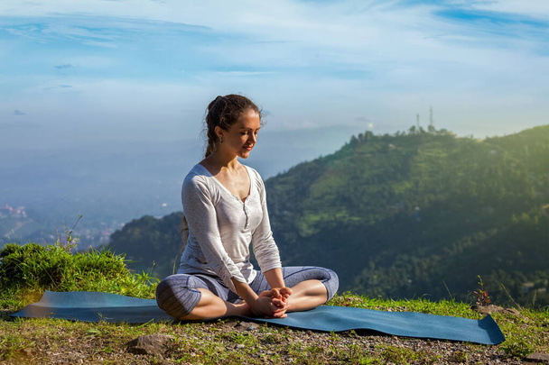 Donna in forma sportiva pratica yoga asana Baddha Konasana angolo legato posa all'aperto in Himalaya montagne al mattino. Himachal Pradesh, India
 - Foto, immagini