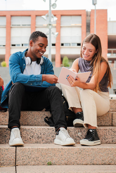 Svisle. Dva multiraciální teenageři, kteří se spolu učí na univerzitním kampusu. Africký americký školák mluví se školačkou o domácím úkolu. Mladí přátelé studují na schodech střední školy - Fotografie, Obrázek
