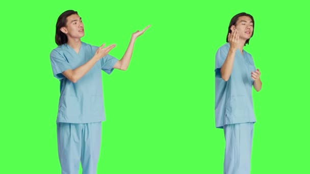 Εργάζεται στην ιατρική βιομηχανία υγείας, ασιατική νοσοκόμα διεξάγει διαφημιστική εκστρατεία σε πράσινο φόντο. Νοσοκόμα με ομοιόμορφα σημεία αριστερά ή δεξιά, που εμφανίζει φρέσκια διαφήμιση. - Πλάνα, βίντεο