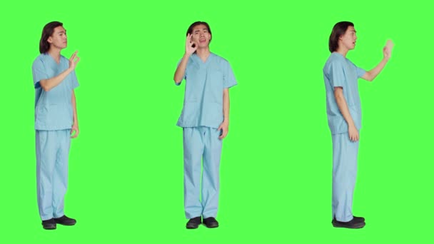 Lékařská asistentka představuje dobré znamení nad celotělovou zelenou zástěnou pozadí, ukazuje souhlas a jako gesto. Zdravotnický pracovník v uniformě dělá schvalovací znamení ve studiu. - Záběry, video