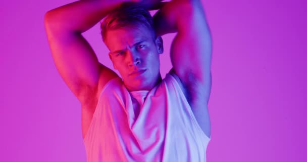 Man, training and stretching in studio for exercise, wellness and muscle health on a purple background. Face or portrait of a young, body builder model with fitness, workout and warmup for sports. - Footage, Video