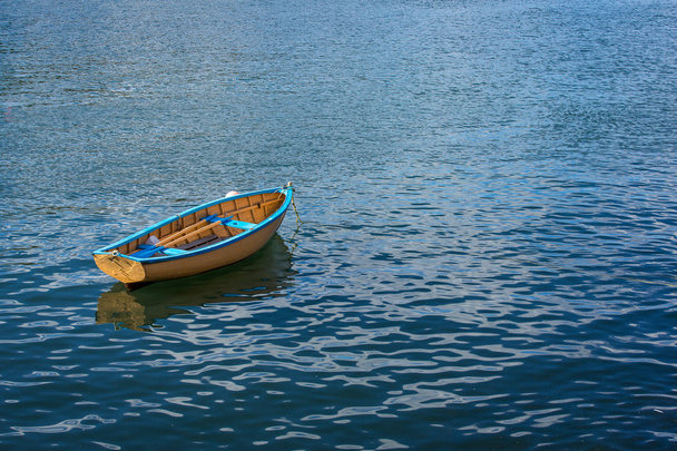 Um pequeno barco de linha sentado calmamente em um porto
 - Foto, Imagem