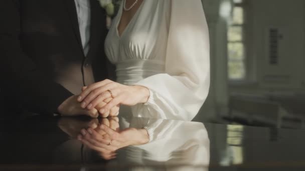 Tiro cortado de casal recém-casado irreconhecível em trajes de casamento elegantes de mãos dadas durante a cerimônia na igreja - Filmagem, Vídeo