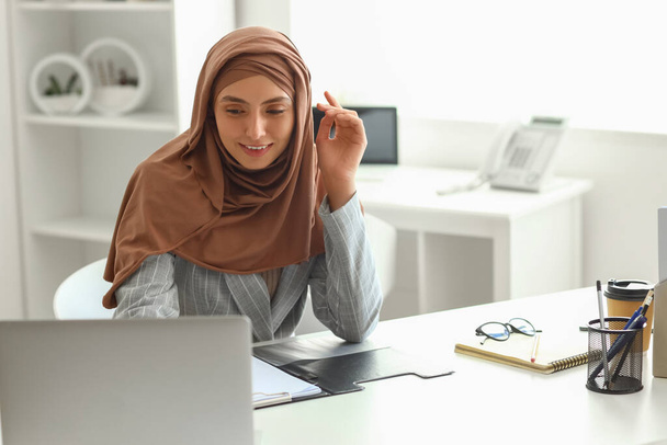 Jovem mulher de negócios muçulmana trabalhando à mesa no escritório - Foto, Imagem