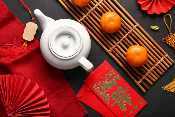 Teepannu mandariineilla ja itämaisilla symboleilla mustalla pohjalla. Uusi vuosi juhla - Valokuva, kuva