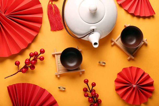 Teapot with cups and oriental symbols on orange background. New Year celebration - Photo, Image
