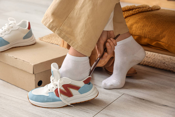 Γυναίκα δοκιμάζει κομψά sneakers στο κατάστημα, closeup - Φωτογραφία, εικόνα