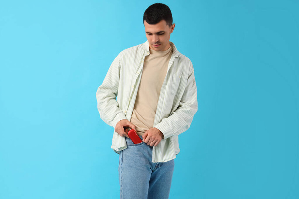Mladý muž s elektronickou cigaretou na modrém pozadí - Fotografie, Obrázek