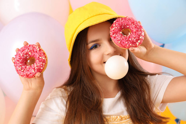 Trendy Mädchen mit Donuts blasen Kaugummi auf gelbem Hintergrund - Foto, Bild