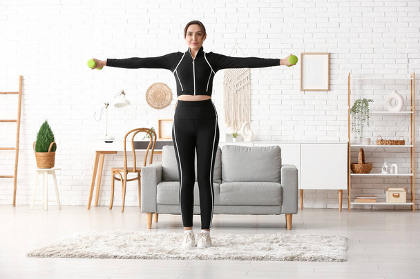 Sportos fiatal nő edzés súlyzókkal otthon - Fotó, kép