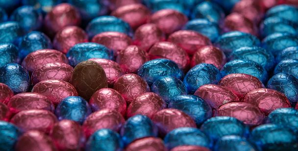 Шоколадные пасхальные яйца, окружающие одно незавернутое стоячее яйцо
 - Фото, изображение