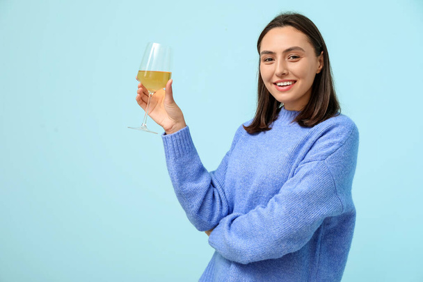 Hermosa joven con copa de vino blanco sobre fondo azul - Foto, Imagen