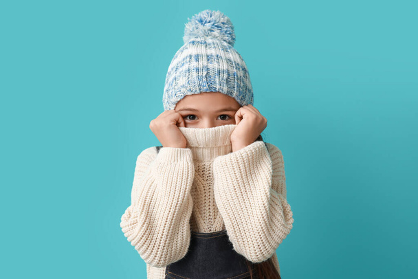 Cute little girl in warm hat on blue background - Photo, Image