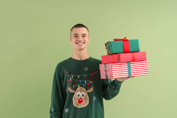 緑の背景にクリスマスギフトボックスを持つ十代の少年 - 写真・画像