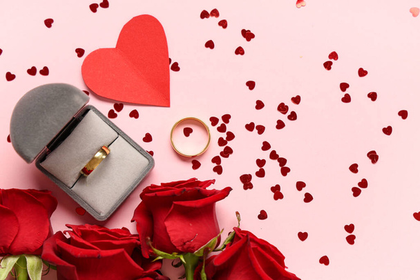 Prachtige compositie met trouwringen en rozenbloemen op roze achtergrond. Valentijnsdag - Foto, afbeelding