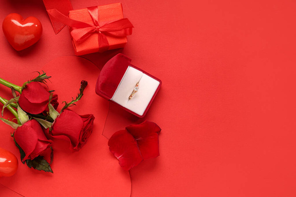 Belle composition avec bague de fiançailles et fleurs roses sur fond rouge. Fête de la Saint Valentin - Photo, image