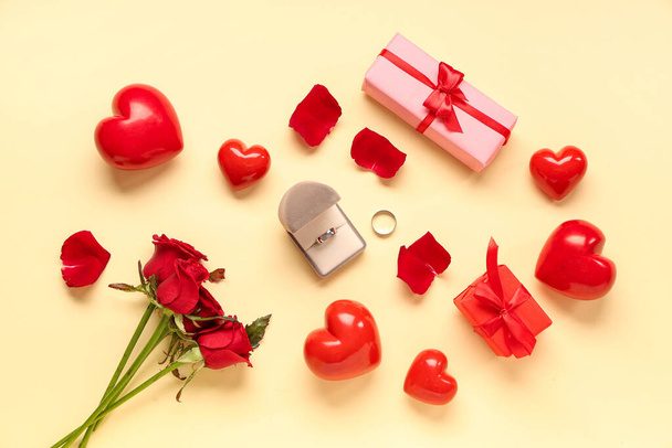Gyönyörű kompozíció jegygyűrűkkel és rózsa virágokkal sárga háttérrel. Valentin-napi ünneplés - Fotó, kép