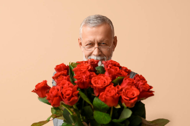 Mature man with bouquet of roses for Valentine's day on beige background - Photo, Image