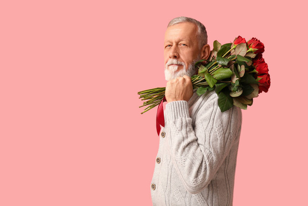 Hombre maduro con ramo de rosas sobre fondo rosa. Celebración de San Valentín - Foto, Imagen
