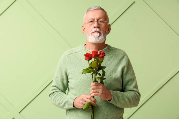 Starší muž s růžovými květy na zeleném pozadí. Valentýnská oslava - Fotografie, Obrázek