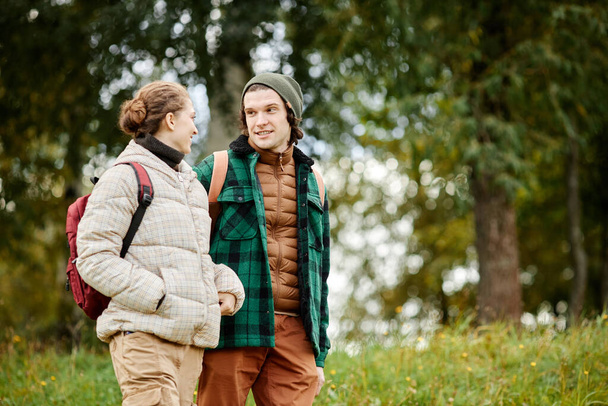 Retrato de la cintura hacia arriba de una joven pareja sonriente disfrutando de un paseo en el bosque de otoño, espacio para copiar - Foto, imagen