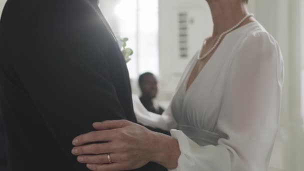 Tilt up slowmo van pasgetrouwde blanke volwassen paar zoenen tijdens mooie huwelijksceremonie in witte kapel - Video