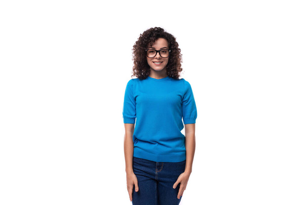 φιλική νεαρή σγουρή μελαχρινή γυναίκα σε μπλε t-shirt σε λευκό φόντο. - Φωτογραφία, εικόνα