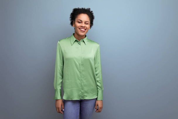 νεαρή θετική χαμογελαστή ισπανόφωνη μελαχρινή κυρία ντυμένη με ένα πράσινο κομψό πουκάμισο στο παρασκήνιο με χώρο αντίγραφο. - Φωτογραφία, εικόνα