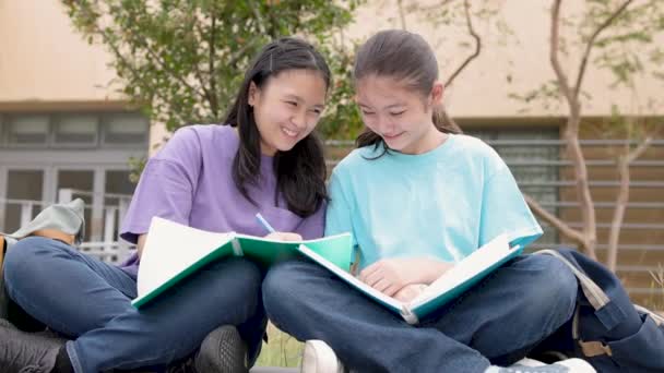 szczęśliwy Azji student dziewczyny studiować i dyskutować prace domowe w szkole - Materiał filmowy, wideo