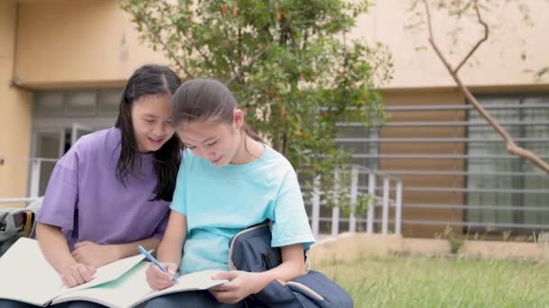 Щасливі азіатські студентки вивчають і обговорюють домашнє завдання в школі - Кадри, відео