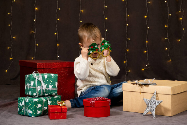 Pieni hauska poika leikkii juhlava lasit jouluna. - Valokuva, kuva