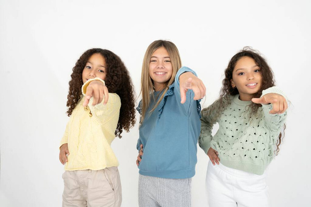 kolme teini-ikäistä tyttöä osoittaa kameraa tyytyväisellä, itsevarmalla, ystävällisellä hymyllä, valitsemalla sinut - Valokuva, kuva