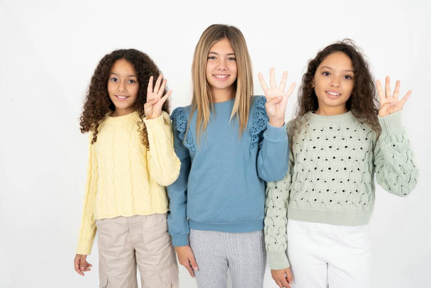 3人のティーンエイジャーの女の子が 自信と幸せを笑いながら 指4番を指で指で指さして. - 写真・画像