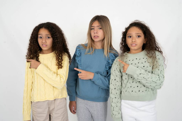 drie tiener meisjes Pointing opzij bezorgd en nerveus met wijsvinger, bezorgdheid en verrassing concept. - Foto, afbeelding