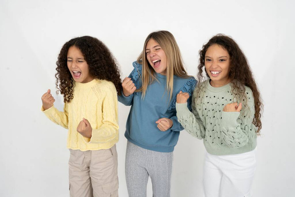 три дівчинки-підлітки дуже щасливі і схвильовані, роблячи жест переможця з піднятими руками, посміхаючись і кричачи на успіх. Концепція святкування. - Фото, зображення