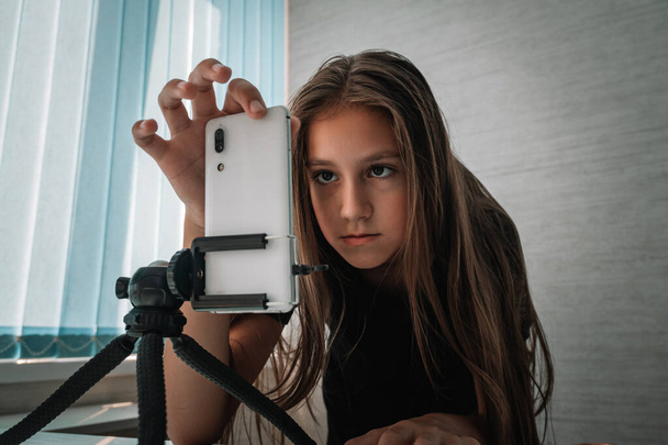 10代の少女が携帯電話で自分自身のビデオを撮影しました. 少女はカメラの前で ストーリーを記録し. - 写真・画像