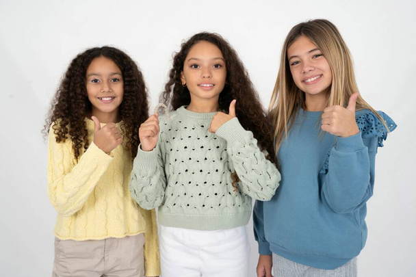 trzy nastolatki trzymające niewidzialny aparat na zęby i podnoszące kciuk, rekomendujące to nowe leczenie. Koncepcja opieki stomatologicznej. - Zdjęcie, obraz