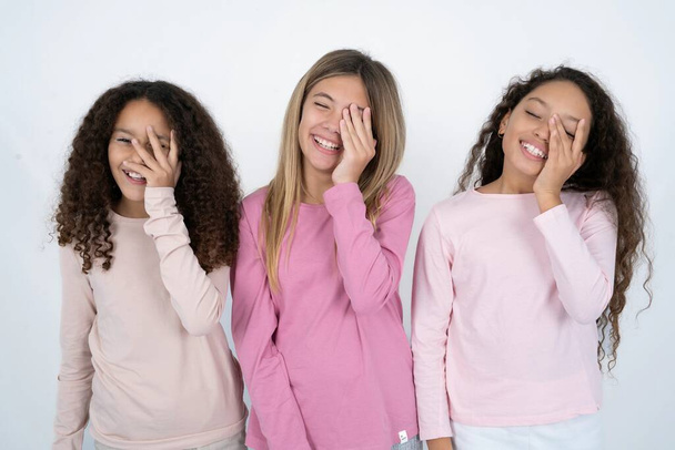 drie tiener meisjes maakt gezicht palm en glimlacht breed, giechelt positief hoort grappige grap poses - Foto, afbeelding