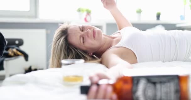 Mujer borracha con una botella de alcohol en la cama, de cerca. Mañana se despierta después de una fiesta, dolor de cabeza por resaca - Imágenes, Vídeo
