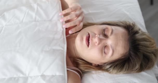 Een vrouw wordt wakker en kijkt angstig onder de dekens, close-up. Onverwachte menstruatiecyclus of bloeding, slow motion - Video