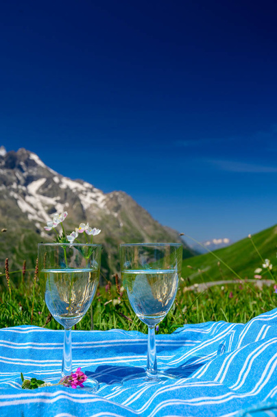 Szemüveg száraz fehér Roussette de Savoie vagy Vin de Savoie bor a Savoy régió szolgált virágzó alpesi rétek Col du Lautaret az Alpok hegyek nyáron, Franciaország. - Fotó, kép