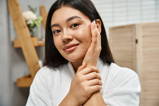 portret van gelukkig jong aziatisch vrouw met acne aanraken wang en kijken naar camera, huidconditie - Foto, afbeelding