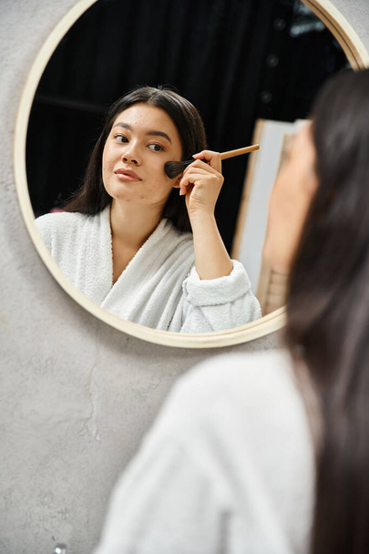 mujer asiática joven aplicando polvo facial sobre la piel propensa al acné con cepillo en el espejo, maquillaje - Foto, imagen