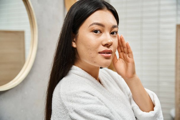 bruneta mladý asijské s akné-náchylný kůže stojící v moderní koupelně a při pohledu na kameru - Fotografie, Obrázek