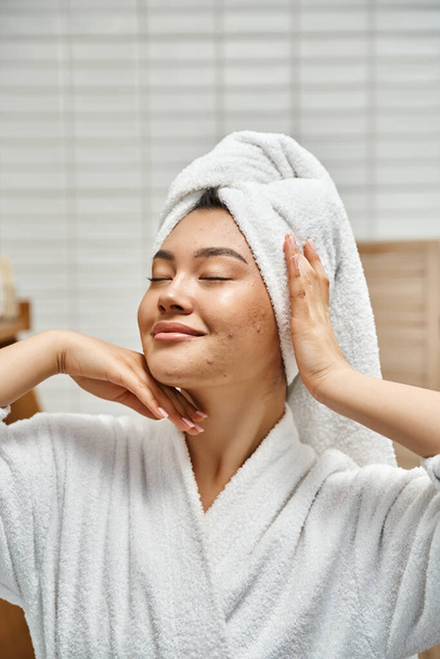vertical tiro de satisfeito jovem asiático mulher com acne propenso pele com toalha branca na cabeça no banheiro - Foto, Imagem