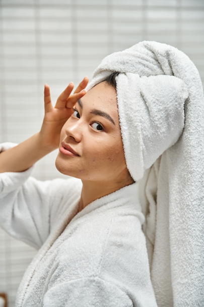 giovane donna asiatica con acne pelle incline con asciugamano sulla testa in posa in bagno a casa, verticale - Foto, immagini