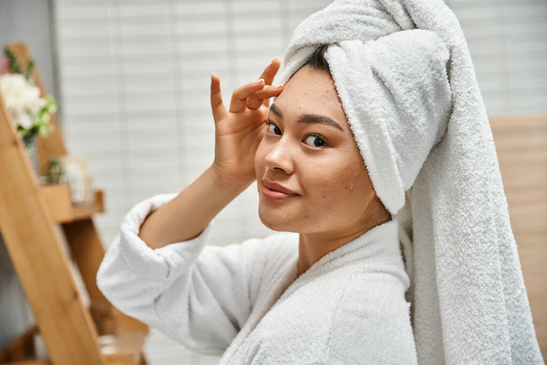fiatal ázsiai nő akne hajlamos bőr törölköző a fejét pózol fürdőszobában otthon, portré - Fotó, kép
