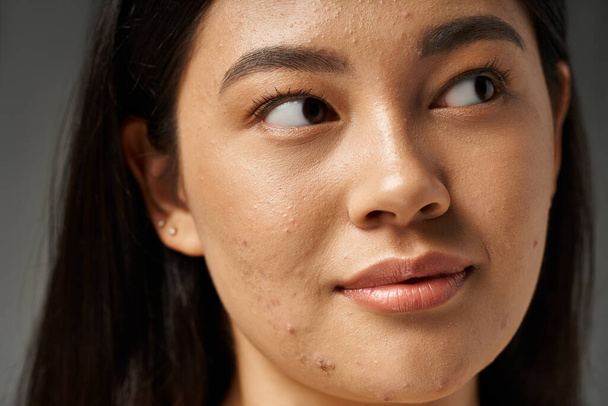 giovane donna asiatica con capelli castani e pelle incline all'acne guardando specchio in bagno, banner - Foto, immagini